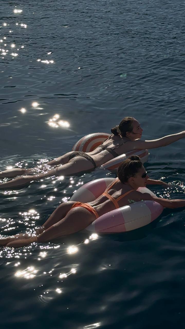 Two women floating on swim rings in open water