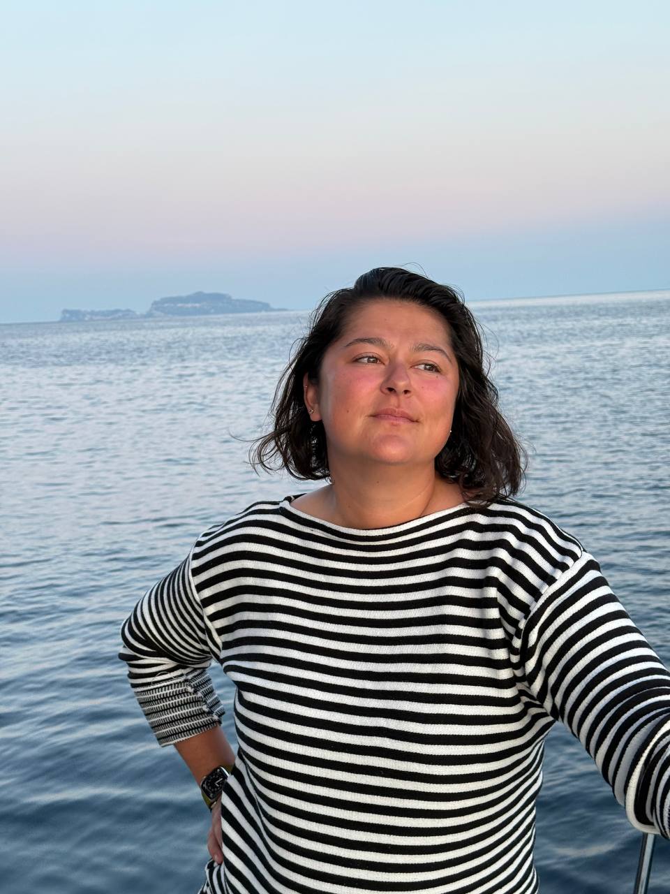 Woman in a striped sweater on the water at dusk